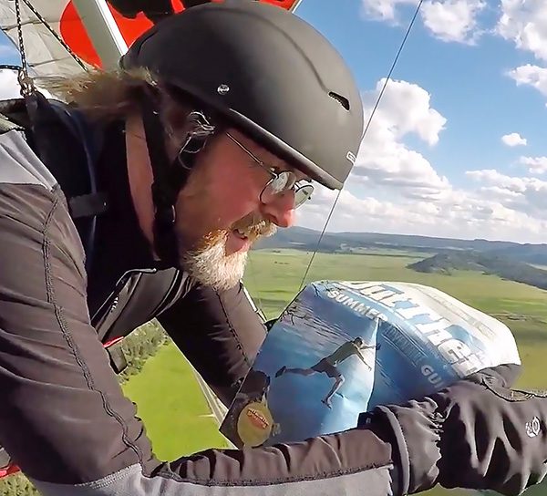 Hang glider reading magazine mid-flight.